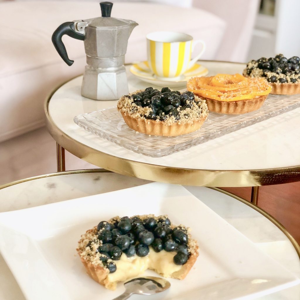 Tartaleta de fruta con arándanos y mango en mesa de mármol con café para la hora de té